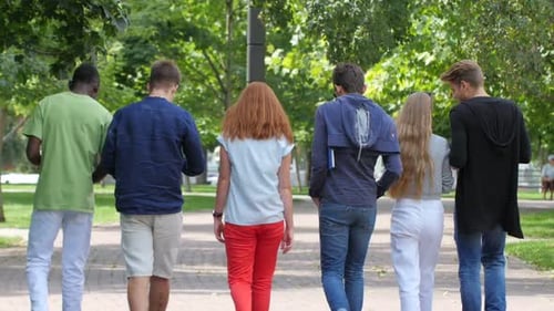 Group of Friends Strolling Through Sunny Park Together