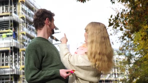 Couple Holding Keys Discussing Plans Near Construction Site