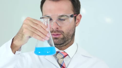 Seriöser Wissenschaftler untersucht blaue Lösung in einer Flasche im Labor