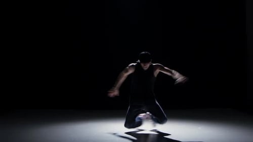 Breakdance-Tänzerin im schwarzen Anzug beginnt Tanz auf Schwarz, Schatten