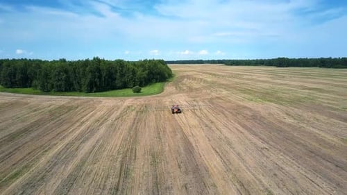 Vuelo sobre un tractor conduciendo en un gran campo cosechado