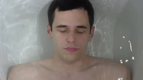 Un homme gît sous l'eau dans le bain