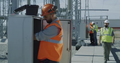 Workers Inspect Electrical Systems at Power Plant