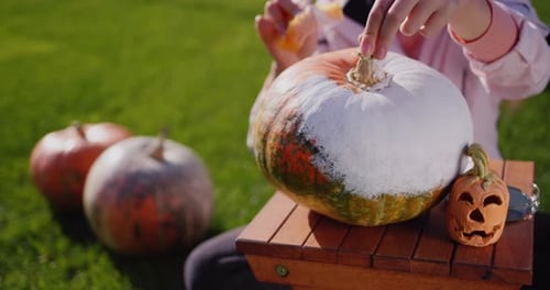 Criança pinta abóboras prepara joias para o Helloween