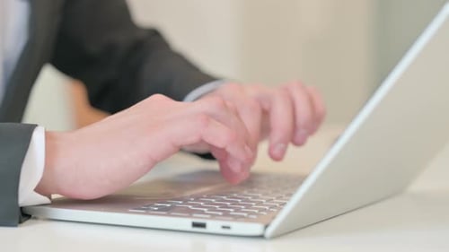 Nahaufnahme eines Geschäftsmannes mittleren Alters, der auf Laptop tippt