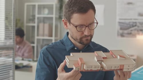 Architect Inspects Building Model in Bright Office