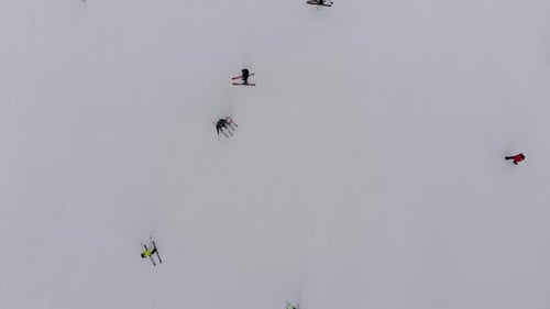 Aerial Top View of Skiers Go Down the Ski Slope on Ski Resort in Mountains