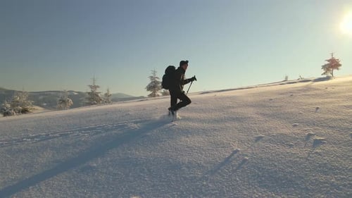 Aerial View of Backpacker Hiking Snowy Mountain Hillside on Cold Winter Morning