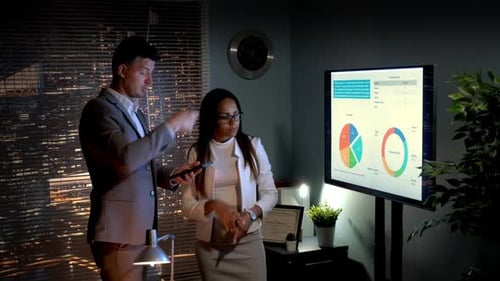 Business People Discussing Financial Data in Office at Night