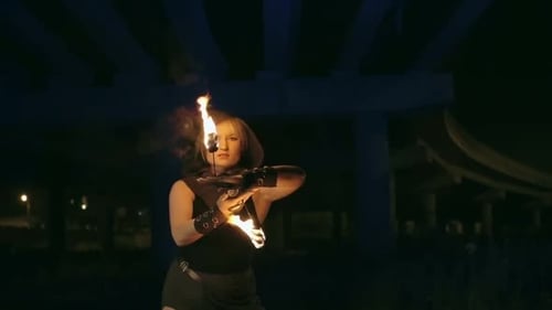 Woman Performs Fire Dance Under Urban Overpass at Night