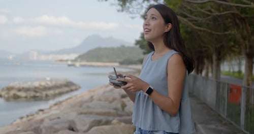 Frau fliegt Drohne und steht am Meer