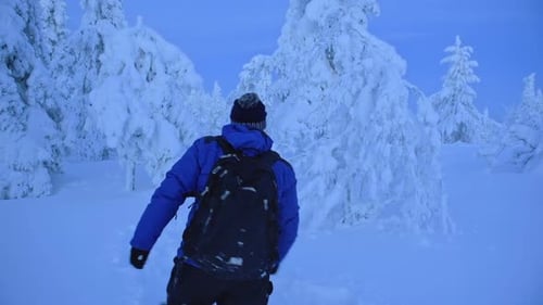 Ein Mann in blauer Winterkleidung geht knietief im Schnee in der Region Lappland, Finnland. -breit