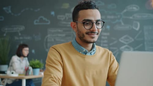 Happy Office Worker Arab Man Using Laptop Computer in Workplace Smiling