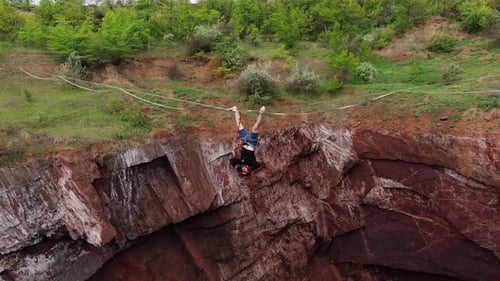 Man Hanging Upside Down from Tightrope Over Gorge