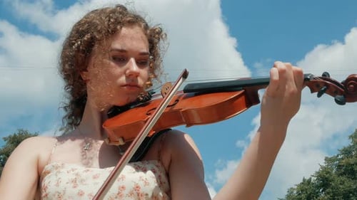 Young Woman Plays Violin Outside on Sunny Day