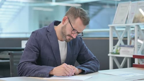 Man Writing at Desk in Office Workplace