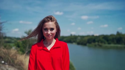Young Woman Smiling by River on Sunny Day