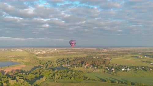 Hot Air Balloon Flying Over Green Countryside Landscape