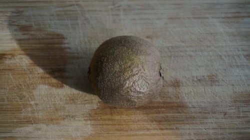 Close up of kiwi being sliced in half on chopping board