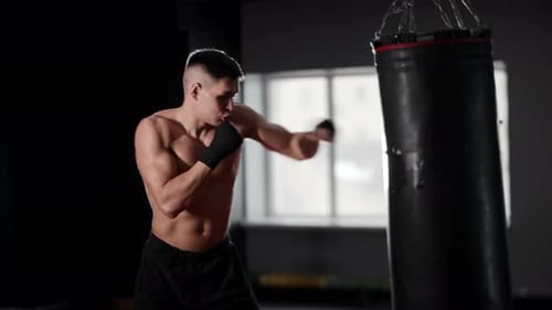 Man Training Hard on Punching Bag in Gym
