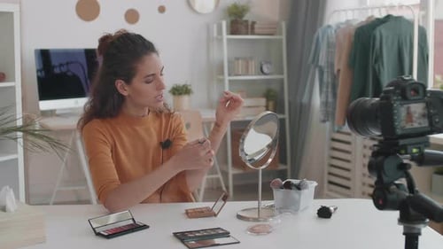 Woman Filming Makeup Tutorial at Table Indoors