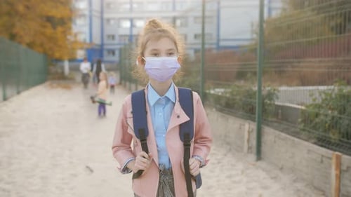 An 8Yearold School Girl Wearing a Protective Medical Mask Returns Home From School