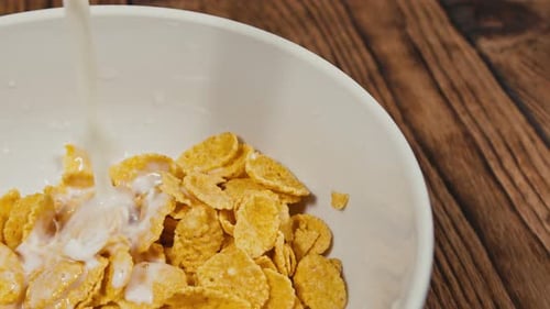 Pouring Milk Over Cereal Flakes in Bowl
