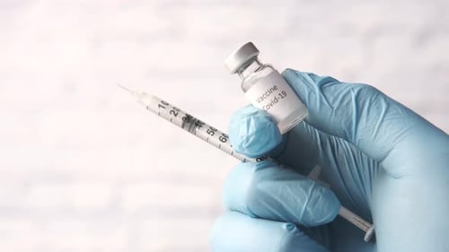 Hand in Latexhandschuhen mit Glasampulle-Impfstoff mit Kopierraum