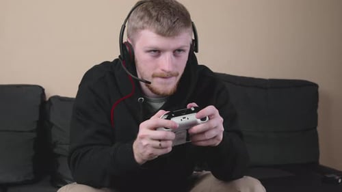 Jovem caucasiano com capuz preto jogando Vídeo com um gamepad