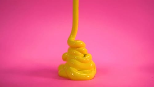 Yellow Fluid Pouring Against Pink Background
