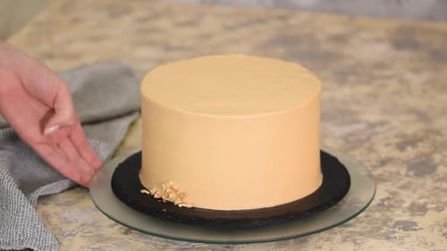 Decorating Delicious Frosted Cake with Chopped Nuts