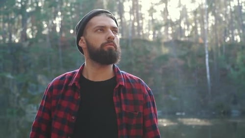 Young Bearded Man with an Axe Walk in Forest. Unshaven Forester with an Ax Outdoors