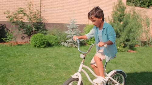 Cute Boy Riding Bike In Backyard