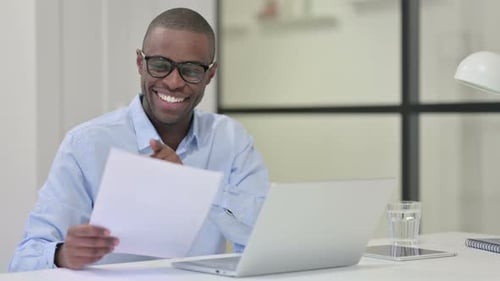 Man Reviews Documents and Smiles with Achievement