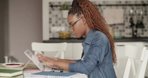 Woman Studying at Table with Tablet and Notebook