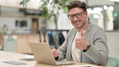 Adult Man Working at Computer Gives Thumbs Up