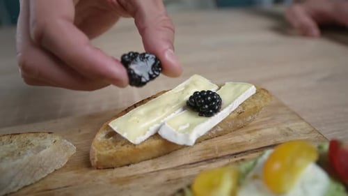 Person Adds Blackberry to Cheese Canape