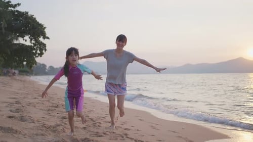 Happy Asian family, Mother playing and having fun with children on the beach during holiday vacation
