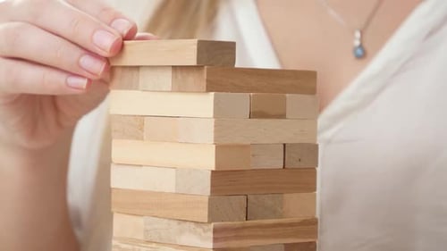 Closeup of Businesswoman Putting Blocks and Bricks of High Tower