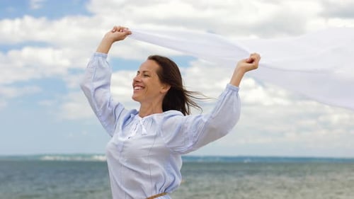 Happy Woman with Shawl Waving in Wind on Beach