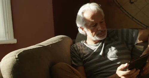 Senior Man Relaxing with Tablet on Sofa