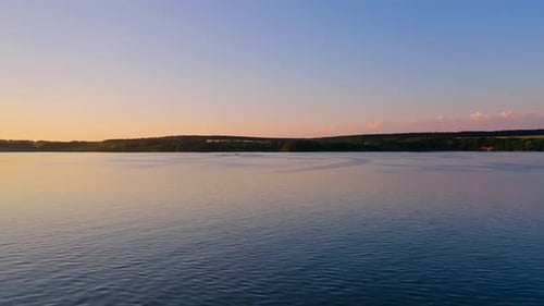 River at sunset. Flight over the tranquil water in the evening.