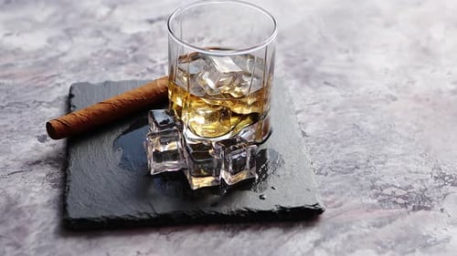 Whiskey, Ice, and Cigar Rotating on Slate