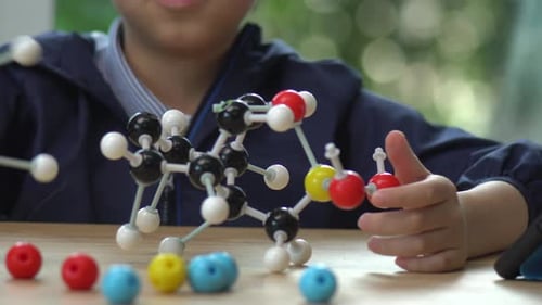 Close Up Of Asian Child Constructing Molecular Model In Science Classroom