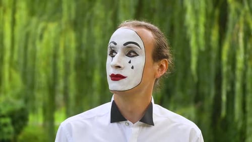 Lustiger Pantomime mit Blick in die Kamera auf grünem Hintergrund in einem Park