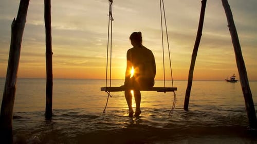 Girl on a Swing By the Seashore on Sunset