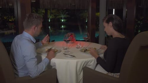 A man and woman couple dining inside at dinner at a tropical island resort