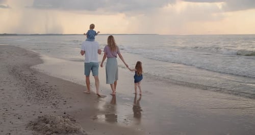 Young Family of Four Walking Down the Beach