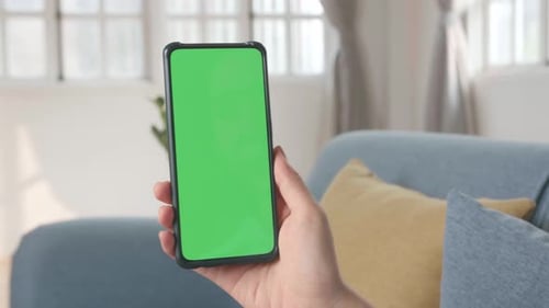 Hand Female Holding Smartphone With Green Screen In Living Room