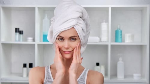 Woman Applying Cream in Bathroom with Towel